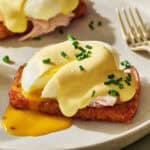 hash brown eggs benedict with a runny egg and topped with cottage cheese hollandaise and chives